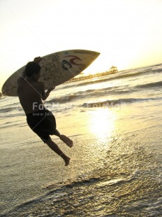 Fair Trade Photo 15-20 years, Activity, Beach, Colour image, Evening, Friendship, Fun, Jumping, One boy, Outdoor, People, Peru, Sand, Sea, South America, Sport, Surfboard, Vertical, Water