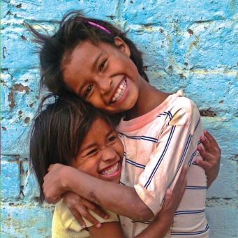 Fair Trade Photo Greeting Card 5-10_years, Activity, Caring, Colour image, Cute, Day, Emotions, Friendship, Fun, Girl, Happiness, Horizontal, Hug, Joy, Looking at camera, Love, Multi-coloured, Outdoor, People, Peru, Portrait halfbody, Portraits, Smile, Smiling, South America, Street, Streetlife, Together, Two children, Two girls, Wall, Warmth, Youth