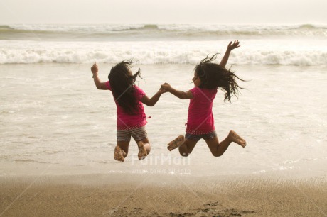 Fair Trade Photo 10-15 years, 5 -10 years, Activity, Beach, Children, Colour image, Day, Emotions, Friendship, Happiness, Holding hands, Holiday, Horizontal, Jumping, Ocean, People, Peru, Playing, Sand, Sea, Seasons, Sister, South America, Summer, Twins, Two, Water