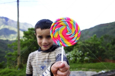 Fair Trade Photo Activity, Birthday, Colour image, Day, Focus on foreground, Giving, Horizontal, Lollypop, Looking at camera, Multi-coloured, One boy, Outdoor, People, Peru, Portrait halfbody, Smiling, South America