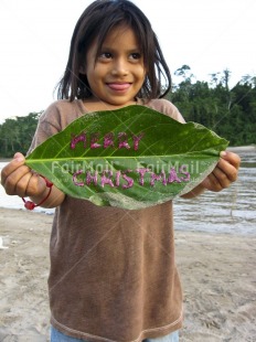 Fair Trade Photo 5-10 years, Activity, Casual clothing, Christmas, Clothing, Colour image, Day, Giving, Latin, Leaf, Letter, Looking away, One girl, Outdoor, People, Peru, Portrait halfbody, River, Rural, Smiling, South America, Standing, Vertical