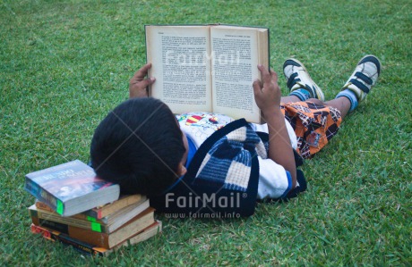 Fair Trade Photo 5 -10 years, Activity, Book, Colour image, Education, Grass, Latin, Looking away, One boy, People, Peru, Portrait fullbody, Reading, Relaxing, School, South America
