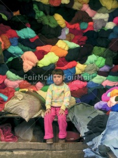 Fair Trade Photo 5-10 years, Activity, Casual clothing, Clothing, Colour image, Colourful, Day, Emotions, Latin, Looking at camera, Market, Multi-coloured, One girl, Outdoor, People, Peru, Portrait fullbody, Sadness, Sitting, South America, Vertical