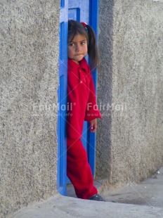 Fair Trade Photo 5-10 years, Activity, Blue, Casual clothing, Clothing, Colour image, Day, Door, House, Latin, Looking at camera, One girl, Outdoor, People, Peru, Portrait fullbody, Red, South America, Standing, Vertical, Welcome home