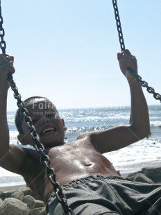 Fair Trade Photo 5-10 years, Activity, Beach, Colour image, Dailylife, Day, Fun, Looking at camera, Multi-coloured, One boy, Outdoor, People, Peru, Playing, Portrait halfbody, Sea, Seasons, Smile, Smiling, South America, Sport, Summer, Swing, Swinging, Vertical