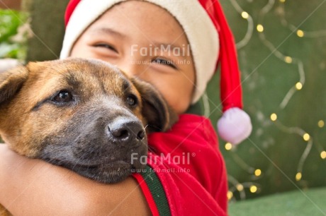 Fair Trade Photo Activity, Adjective, Animal, Animals, Body, Celebrating, Child, Christmas, Christmas decoration, Christmas hat, Dog, Emotions, Happiness, Happy, Horizontal, Light, Nature, Object, People, Present, Puppy, Santaclaus, Smile