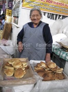 Fair Trade Photo Activity, Bread, Clothing, Colour image, Dailylife, Emancipation, Entrepreneurship, Food and alimentation, Looking at camera, Market, Multi-coloured, Old age, One woman, People, Peru, Portrait halfbody, Saleswoman, Selling, Smiling, Sombrero, South America, Streetlife, Traditional clothing, Urban, Vertical, Working