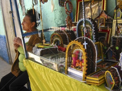 Fair Trade Photo 45-50 years, Activity, Blue, Christianity, Colour image, Cross, Dailylife, Entrepreneurship, Ethnic-folklore, Horizontal, Latin, One woman, Outdoor, People, Peru, Portrait halfbody, Religion, Religious object, Saleswoman, Selling, South America, Spirituality, Streetlife, Working, Yellow