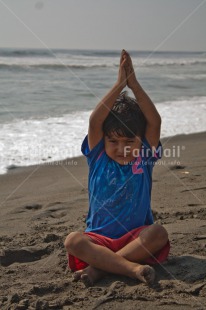Fair Trade Photo 5 -10 years, Activity, Beach, Casual clothing, Clothing, Colour image, Latin, Looking at camera, One boy, Outdoor, People, Peru, Sand, Sea, Sitting, South America, Vertical, Water, Yoga